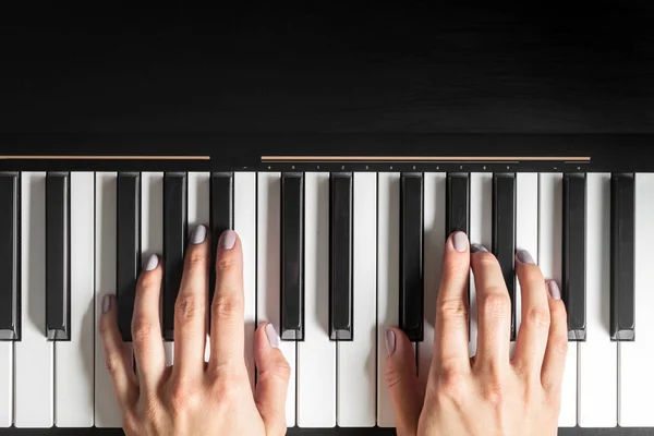 Manos tocando un piano al componer una canción